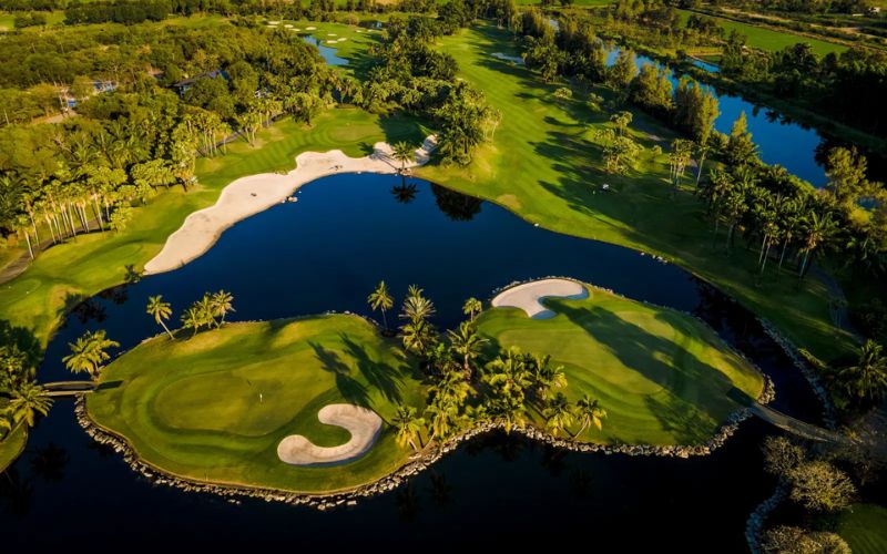 Alpine Golf Club near Bangkok featuring manicured fairways, a lakeside green, and tree-lined landscapes under bright skies.