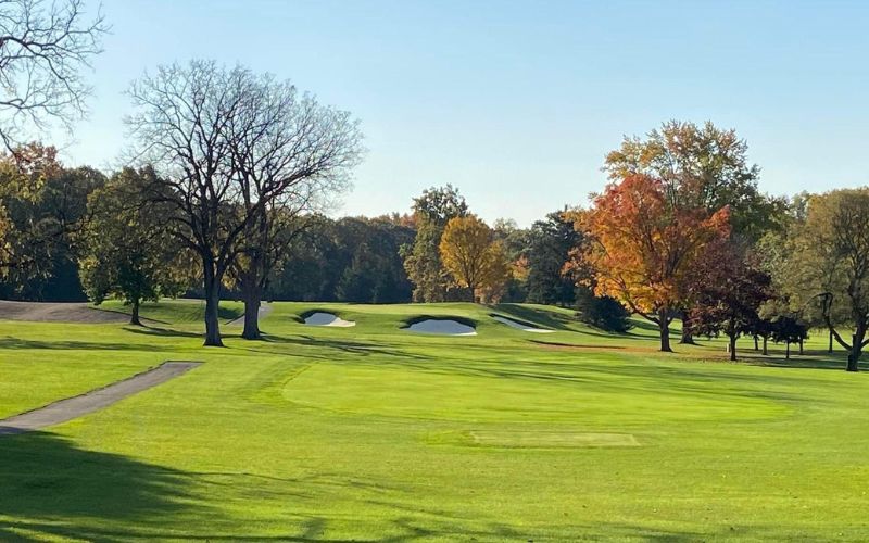 Country Club of Jackson golf course with neatly cut fairways, surrounded by trees with autumn leaves under a bright sky
