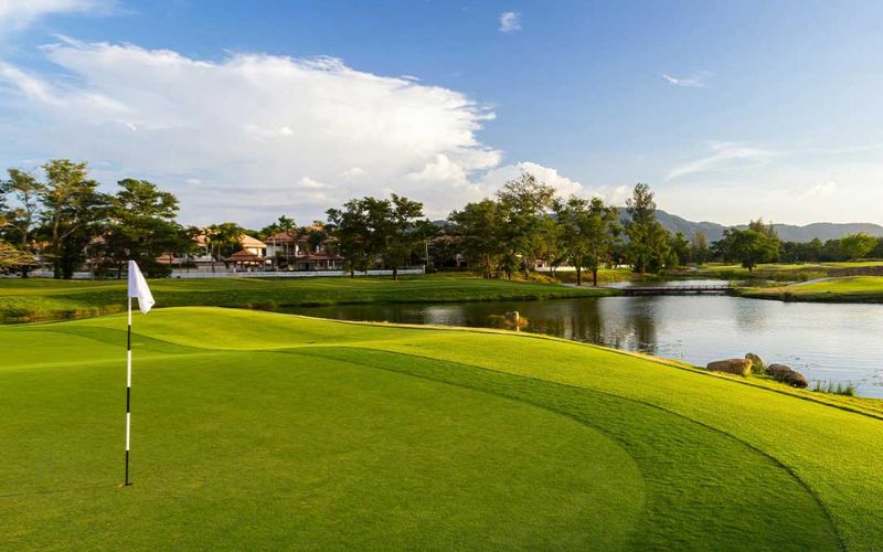 Laguna Golf Phuket with a putting green overlooking a lake and tropical trees under bright skies
