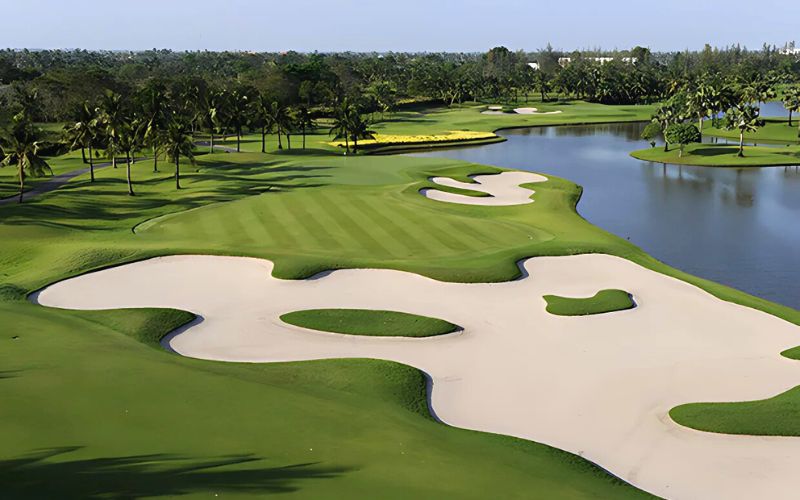 Scenic view of Thai Country Club golf course with wide fairways, sand bunkers, and a lakeside landscape under clear skies.